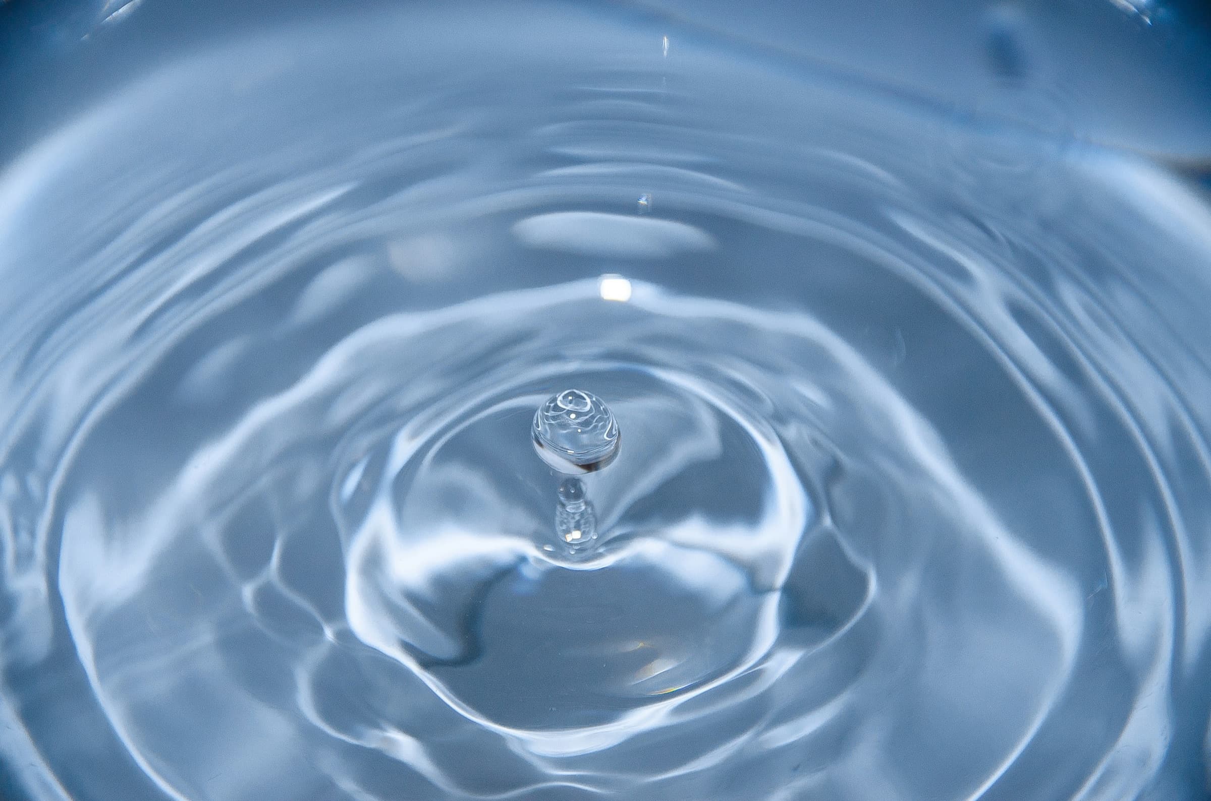Water droplet rippling across a clear surface